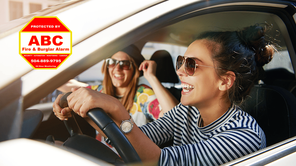 young woman driving car laughing with female friend in passenger seat